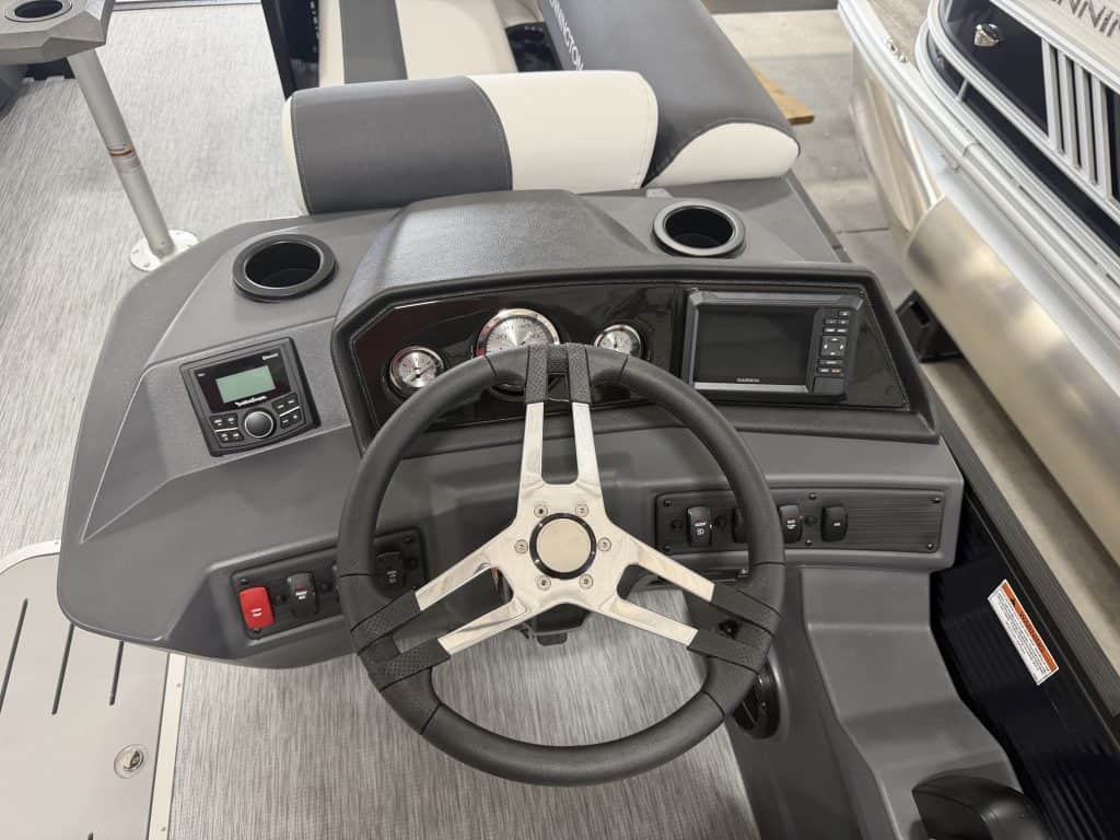 Boat dashboard with steering wheel and control panel at Hall's Sport Center.