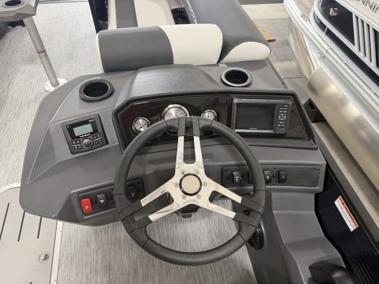 Boat dashboard with steering wheel and control panel at Hall's Sport Center.