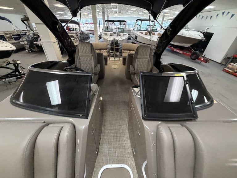 View of boat cockpit with dual steering consoles and seating in showroom.