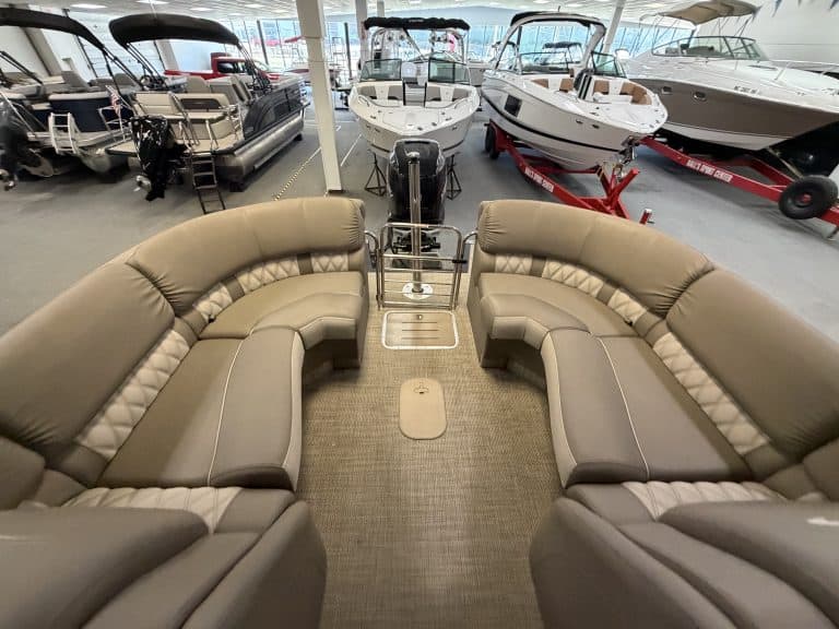 Luxury pontoon boat interior with spacious seating and view of boats in showroom.