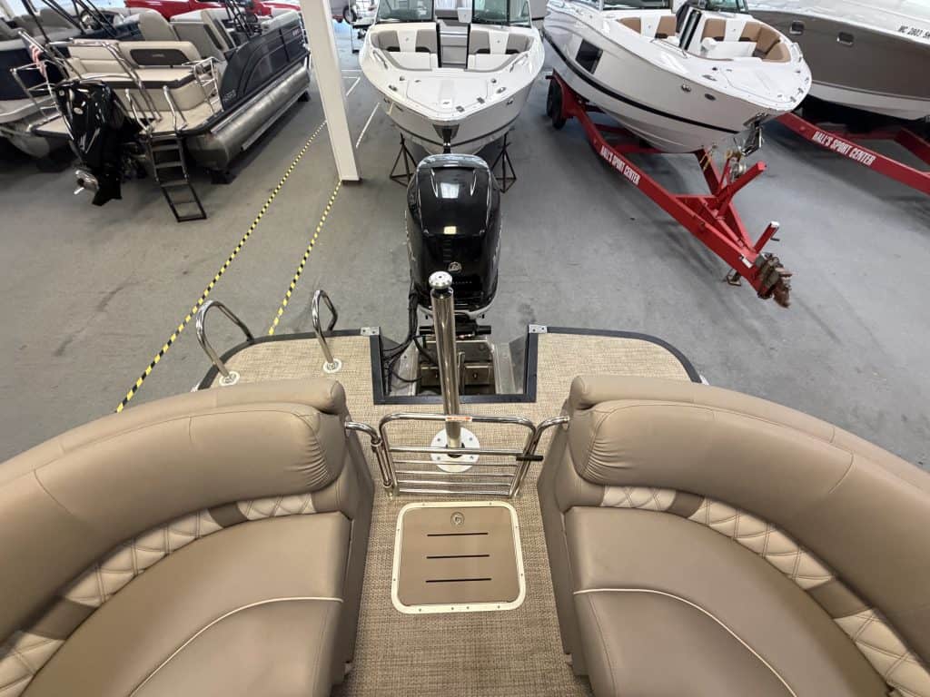 Luxury pontoon boat with beige seating and outboard motor at Hall's Sport Center.