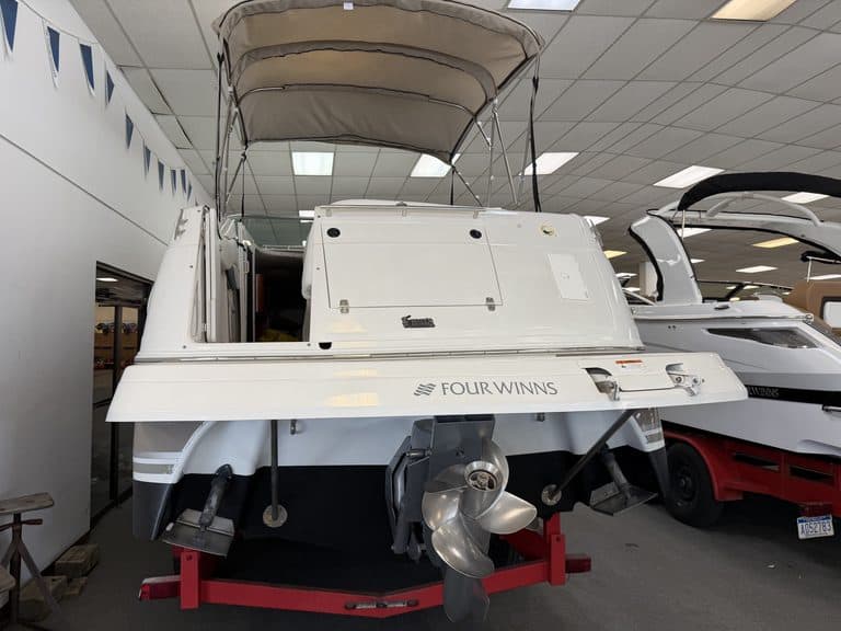 White Four Winns 268 VISTA boat with outboard motor on display.