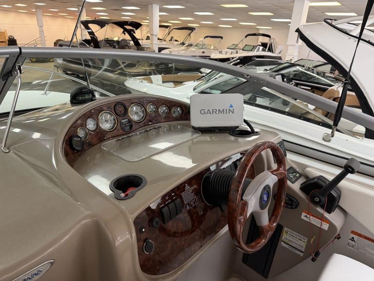 Boat dashboard with Garmin GPS and steering wheel in showroom.