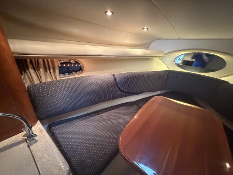Boat interior with seating and wooden table in a 2004 Four Winns 268 VISTA.