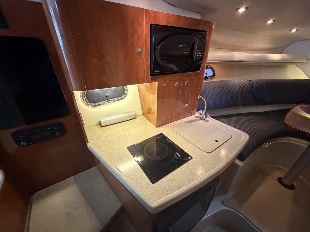 Compact boat kitchen with microwave, stove, and sink inside a vessel.