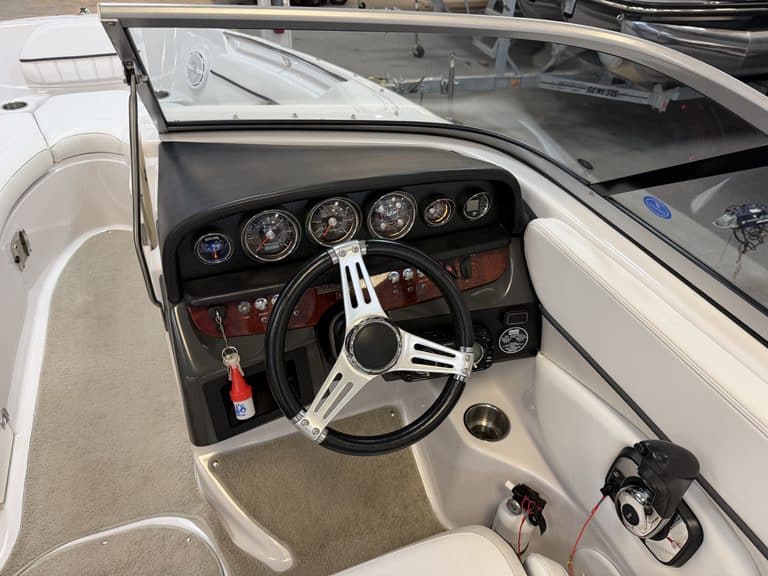 Boat dashboard with gauges and steering wheel in a Four Winns 220 Horizon.