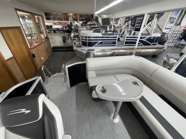 Indoor boat showroom with pontoon boats and seating area at Hall's Sport Center.