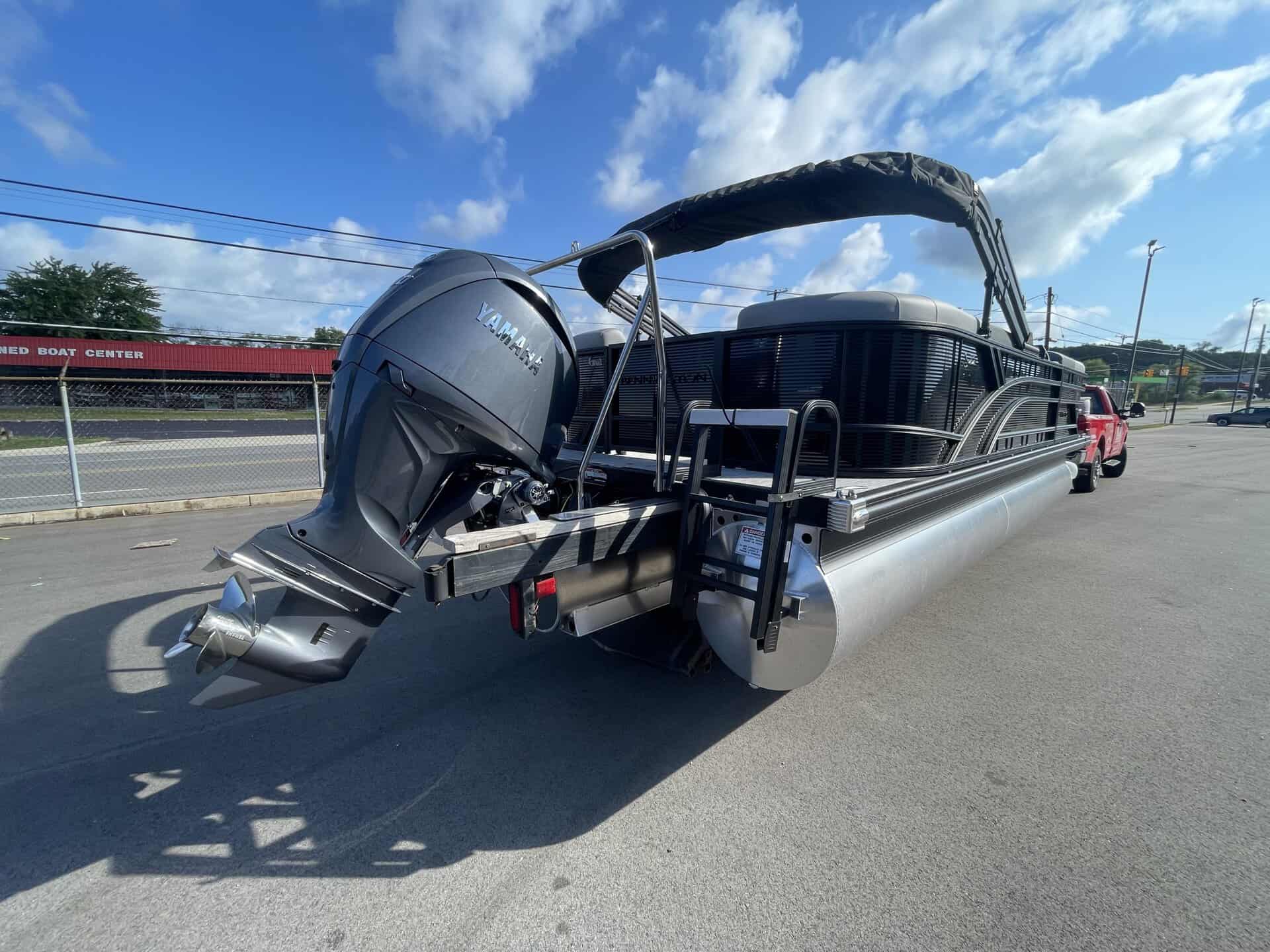 Bennington 22S1 SSR pontoon boat with outboard motor on a parking lot.
