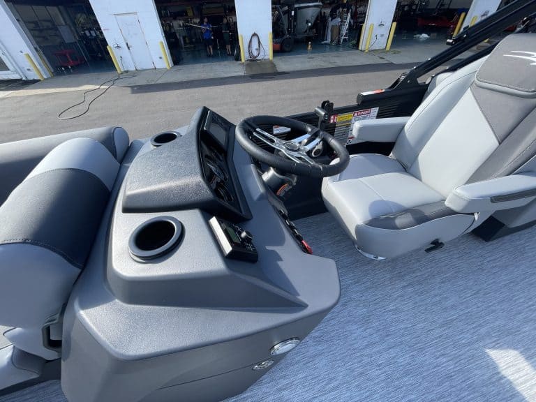 Close-up of boat's cockpit with steering wheel and dashboard.
