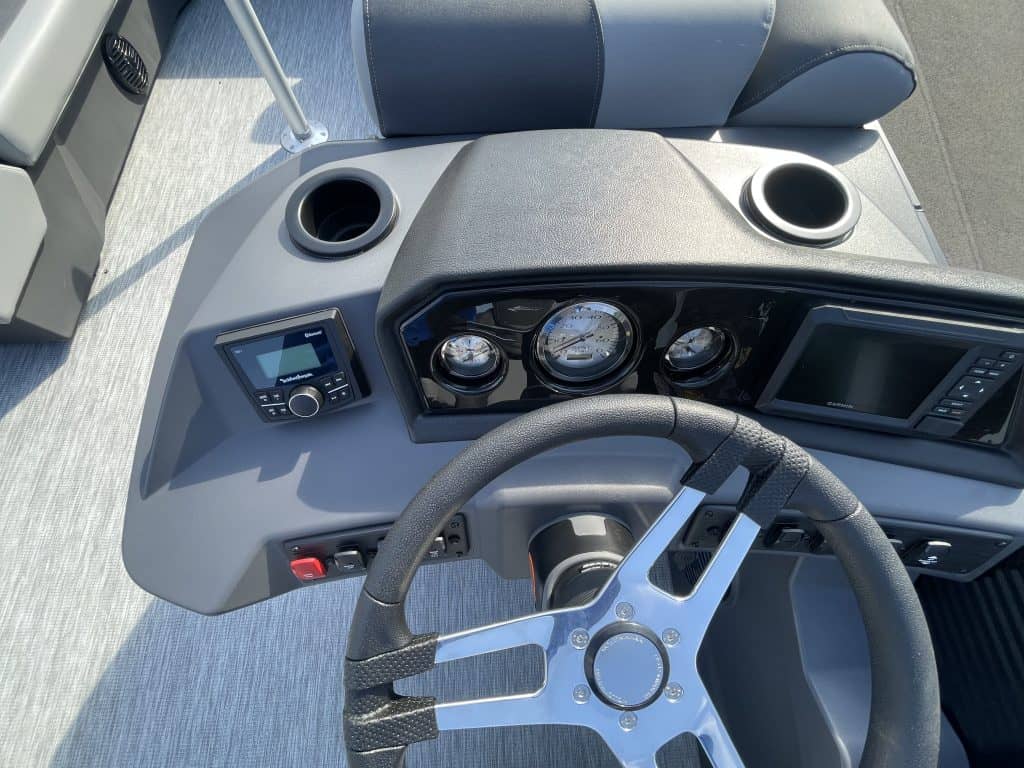 Close-up of boat dashboard with steering wheel and gauges.