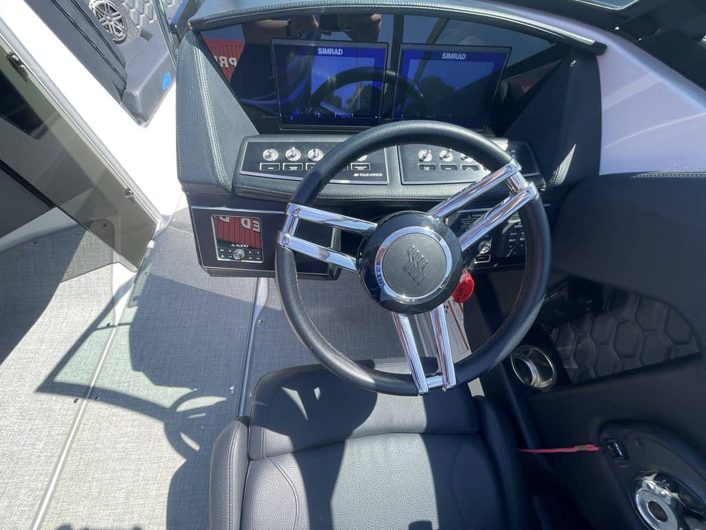 Boat dashboard with steering wheel and digital displays at Hall's Sport Center.