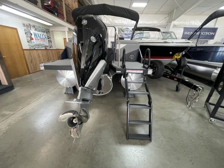 Modern boat with outboard motor and boarding stairs inside showroom.