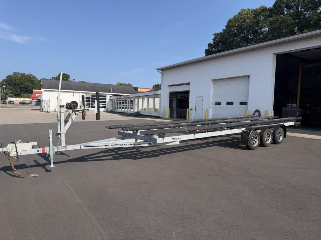 Empty flatbed trailer parked outside Hall's Sport Center building.