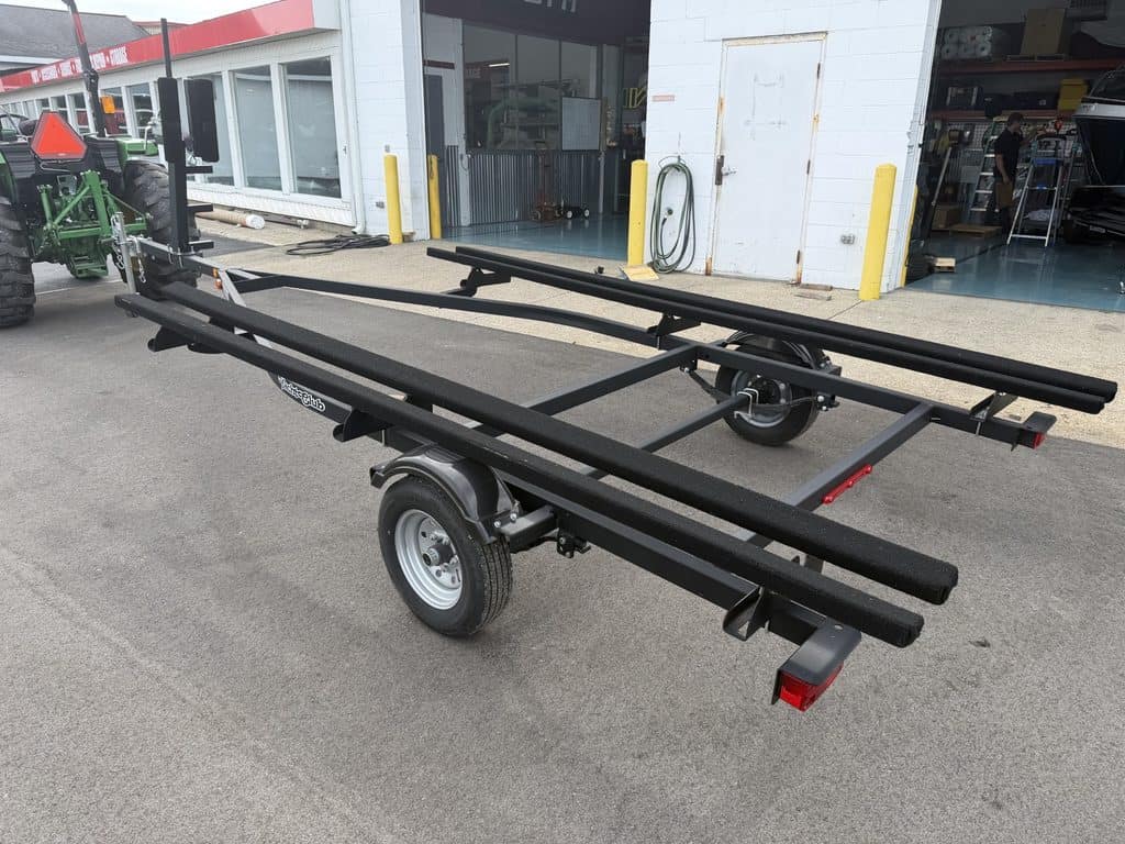Black boat trailer with wheels parked outside a building.