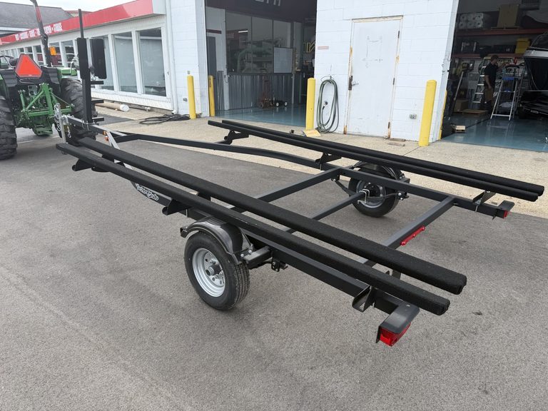 Black boat trailer with wheels parked outside a building.