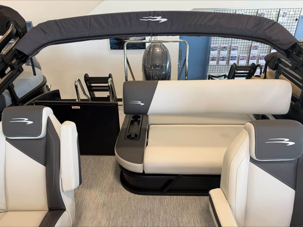 Boat seating area with white and gray cushioned seats and canopy at Hall's Sport Center.