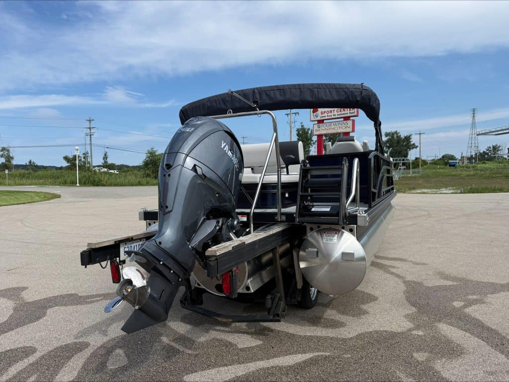 Bennington 22 S1SB pontoon boat with outboard motor on a parking lot.