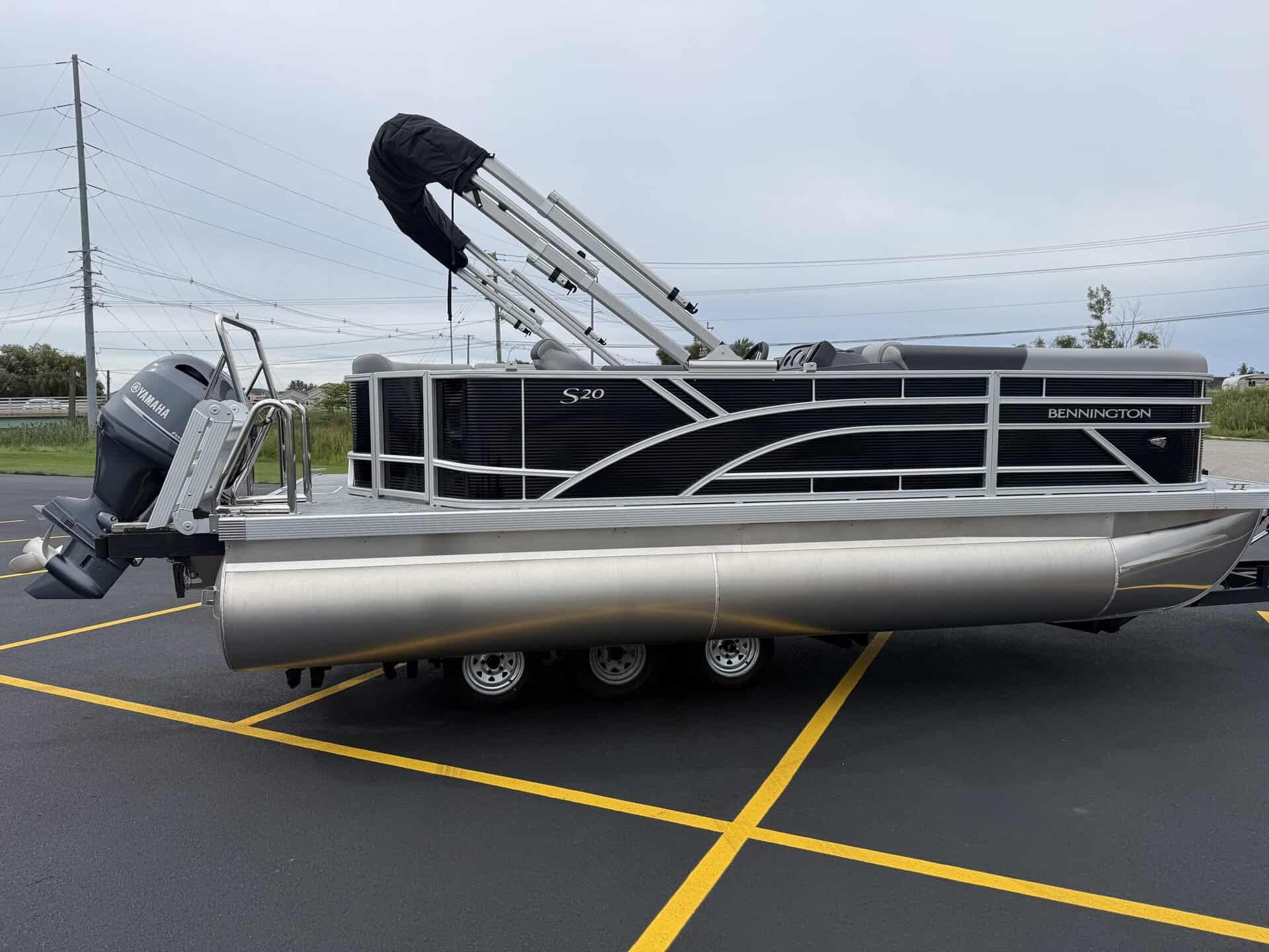Bennington 20 S1L pontoon boat in parking lot with outboard motor.