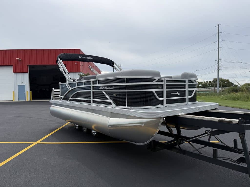 Bennington pontoon boat parked outside Hall's Sport Center in a lot.