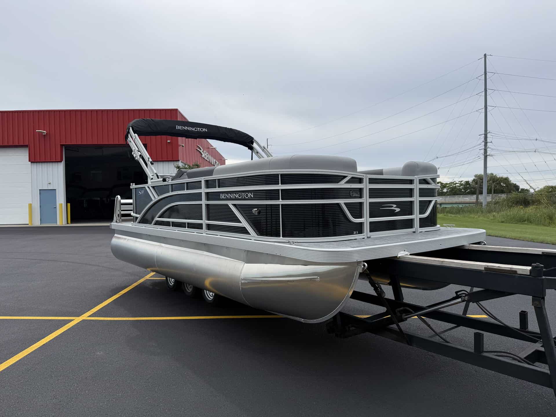 Bennington pontoon boat parked outside Hall's Sport Center in a lot.