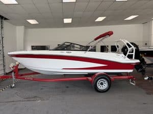 White and red Glastron GX190 boat on trailer in showroom.