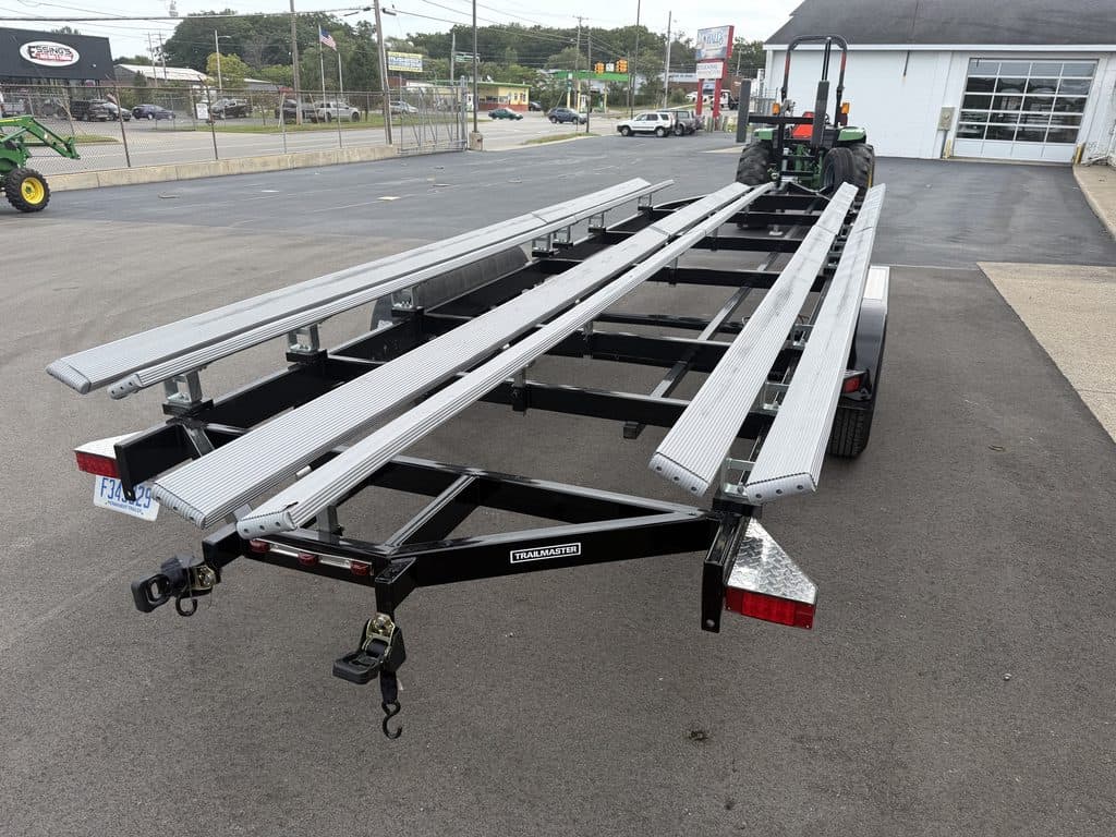 Heavy-duty trailer with aluminum ramps for outdoor equipment transport.