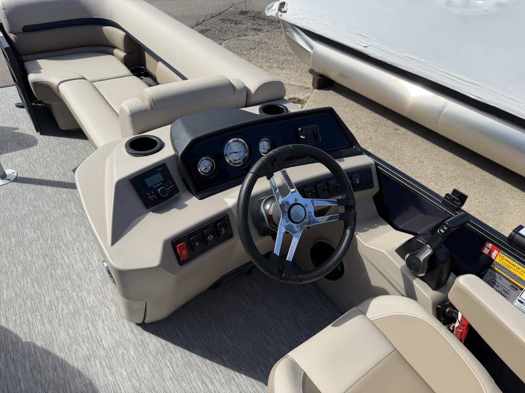 Pontoon boat dashboard with steering wheel and controls at Hall's Sport Center.