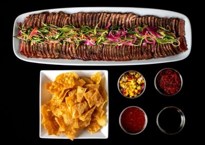 Sliced beef with garnishes and side dishes on a white platter.