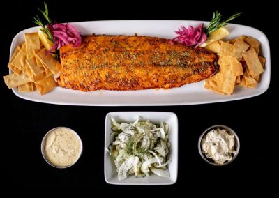 Fresh grilled fish with sides and sauces on a white platter.
