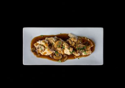 Seafood dish featuring clams, vegetables, and sauce on a white plate.