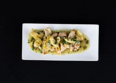 Delicious chicken pasta with herbs and creamy sauce on a white plate.