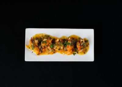 Gourmet dish with vegetables, herbs, and sauce on a white plate.