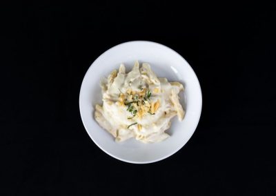 Creamy Alfredo pasta served in a white bowl on a black background.