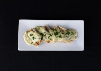 Gourmet chicken fillet with creamy herb sauce on a white plate.