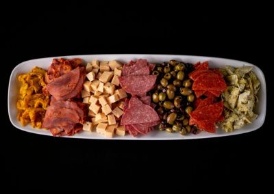 Assorted meats, cheeses, and accompaniments on a white platter.