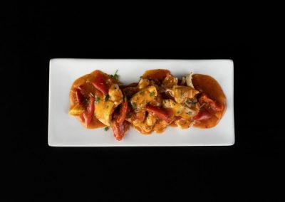 Close-up of flavorful chicken curry with vegetables on a white plate.