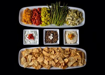 Colorful vegetable platter with dips and chips for healthy snacking.
