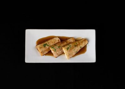 Delicious fish fillets garnished with herbs and served with sauce on a white plate.