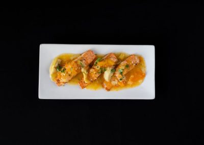 Salmon fillets with mango salsa on a white plate against black background.
