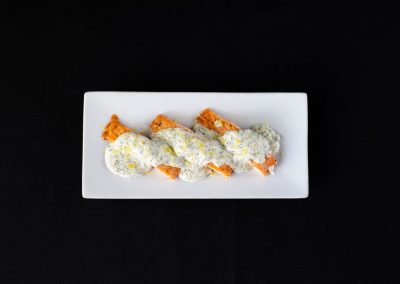 Salmon fillets topped with creamy dill sauce on a white plate.