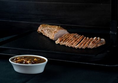 Roast pork sliced with bean soup in a white bowl.