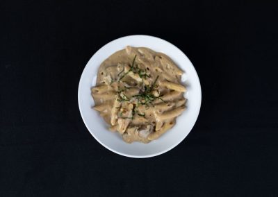 Creamy mushroom pasta served on a white plate with herbs.