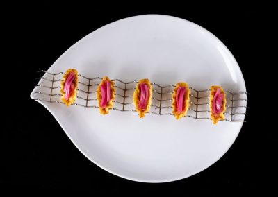 Delicious sushi rolls with pink filling on a white plate with a black background.