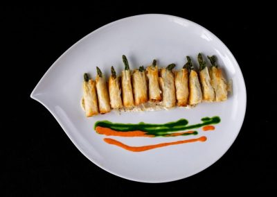Sushi roll with vegetables and colorful sauces on a white plate.