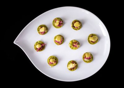 Pistachio and rose cookies on a white leaf-shaped plate.