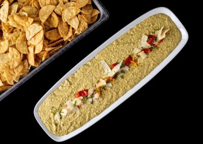 Creamy guacamole dip garnished with tomatoes and cheese, served with crispy chips.