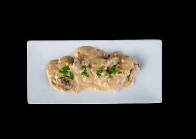 Creamy mushroom dish garnished with fresh herbs on a white plate.