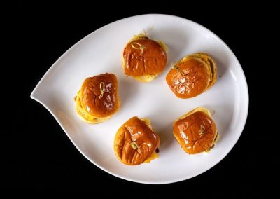 Indian sweets on a white plate with a black background for SEO.
