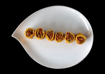 Close-up of rolled herbal or spice products on a white dish.