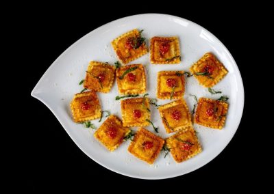 Close-up of crispy Indian snack tikka on white plate.